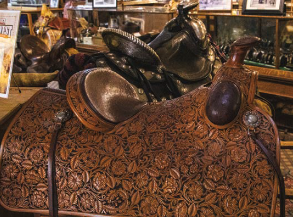 A Mother Hubbard saddle with classic Sheridan tooling, which includes an intricate pattern of flowers, leaves and circular stems.