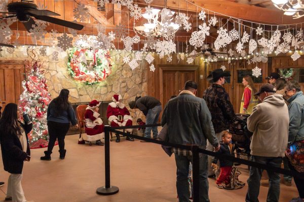 The line to meet Santa and Mrs. Claus. The room is decorated with snowflakes, a Christmas tree and wreath.