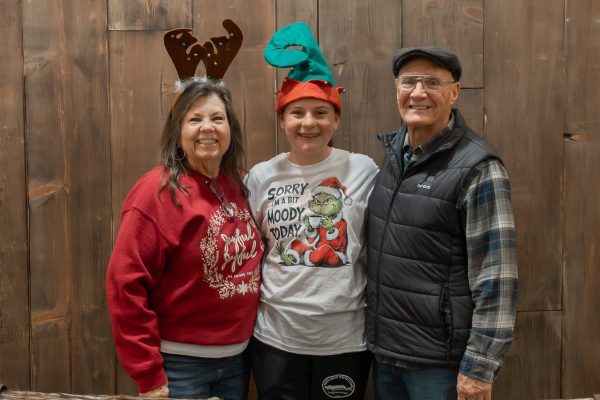 Three visitors taking a photo at the photo booth during Candlelight at the Ranch.