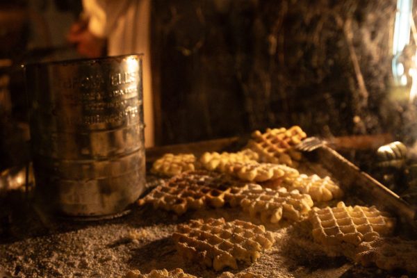 Waffles on a cooking pan sprinkled with powdered sugar.