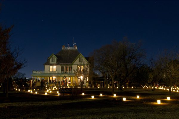 The Queen Anne style Barton House with a line to enter and pathways lit with luminaries.