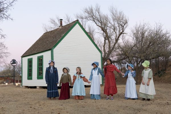 Young school girls holding hands outside the one-room school house.