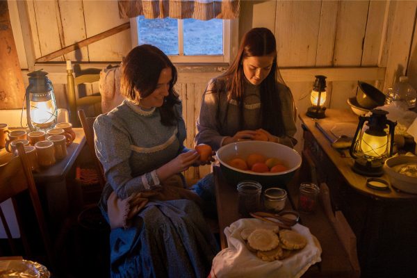Two young women volunteers in pioneer attire decorating oranges in the early 1900s Box & Strip House.