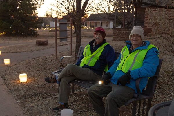Two volunteers sitting on a bench during Candlelight at the Ranch.