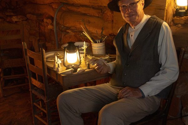 A cowboy sitting with his hand-carved toy.