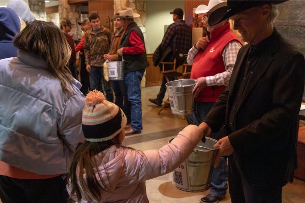 A young girl puts a donation into a donation bucket.