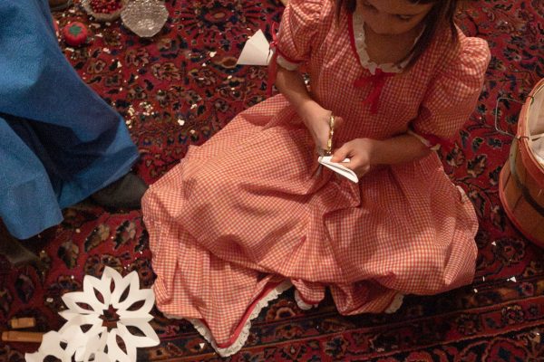 A little girl cuts out hand-made snowflakes in the Barton House.