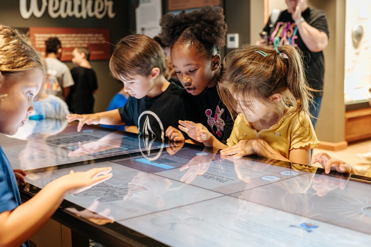 Four children playing a prairie management game inside the Cash Family Ranch Life Learning Center.